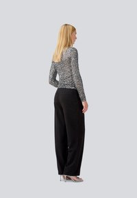 Long-sleeve, multicolored textured top paired with black wide-leg trousers and light blue high-heeled sandals. Shown from the back.