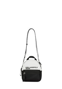 Zaino compatto in materiale bianco e nero, caratterizzato da una forma arrotondata, tasca frontale con zip, tracolla regolabile e logo stampato.