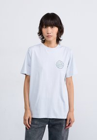 T-shirt bianco in cotone a maniche corte, con un piccolo logo colorato sul lato sinistro del petto. Taglio dritto con scollatura rotonda.
