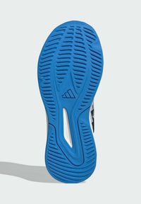 Suola di scarpa in gomma blu con motivo antiscivolo testurizzato, con intersuola bianca e accenti neri. Logo visibile vicino al centro.