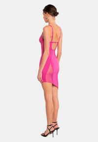 Rosa körpernahes Kleid mit Spaghetti-Trägern, transparenten Seitenpaneelen und einem offenen Rücken. Abgerundet mit minimalen Hardware-Elementen zur Schließe.
