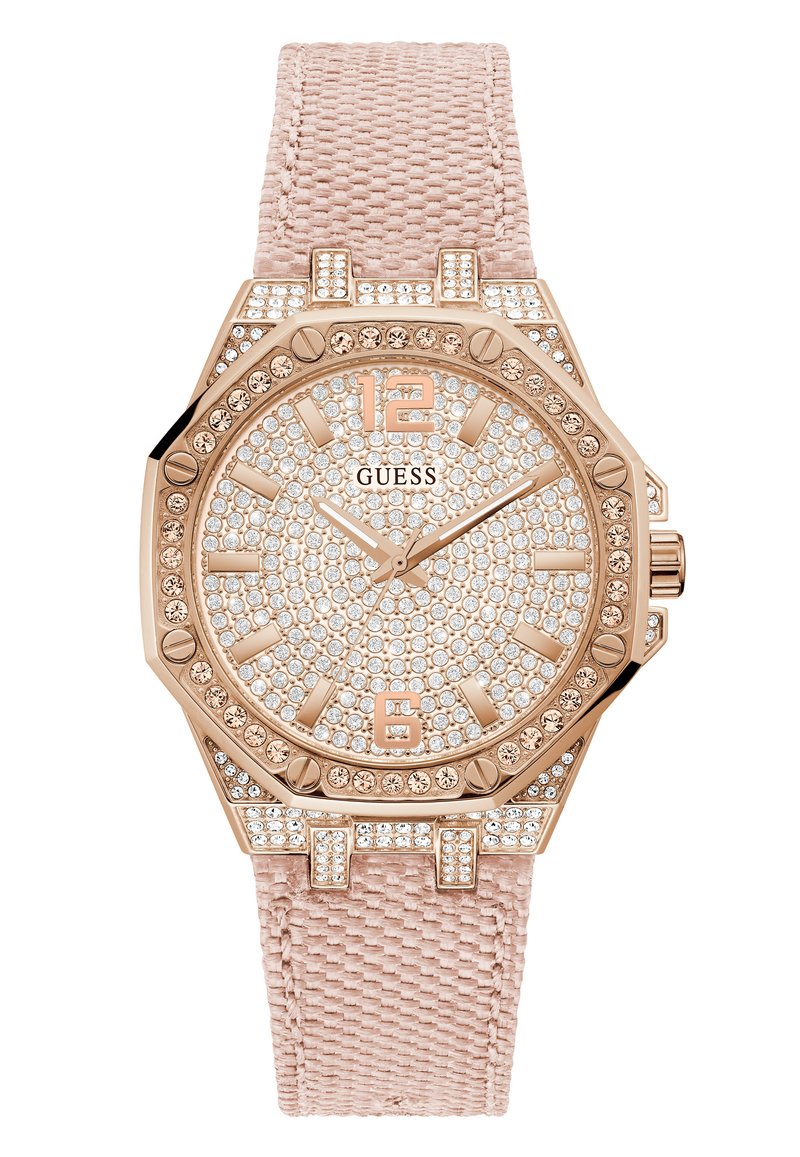 Reloj Guess con caja octagonal en oro rosa, adornos de cristal y una correa de tela de color rosa claro. Los detalles notables incluyen una correa texturizada y acentos numéricos.