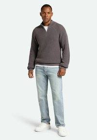 Gray ribbed sweater with a quarter zip, worn over a white shirt, paired with light blue jeans and white sneakers.