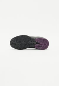 Black athletic shoe sole featuring zigzag tread design, purple accents, and textured surface for traction. Circular branding on side.