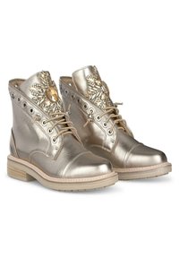 Bottines métalliques dorées avec une texture lisse, perles décoratives, fermeture à lacets à l'avant et bout rond sur une semelle beige texturée.