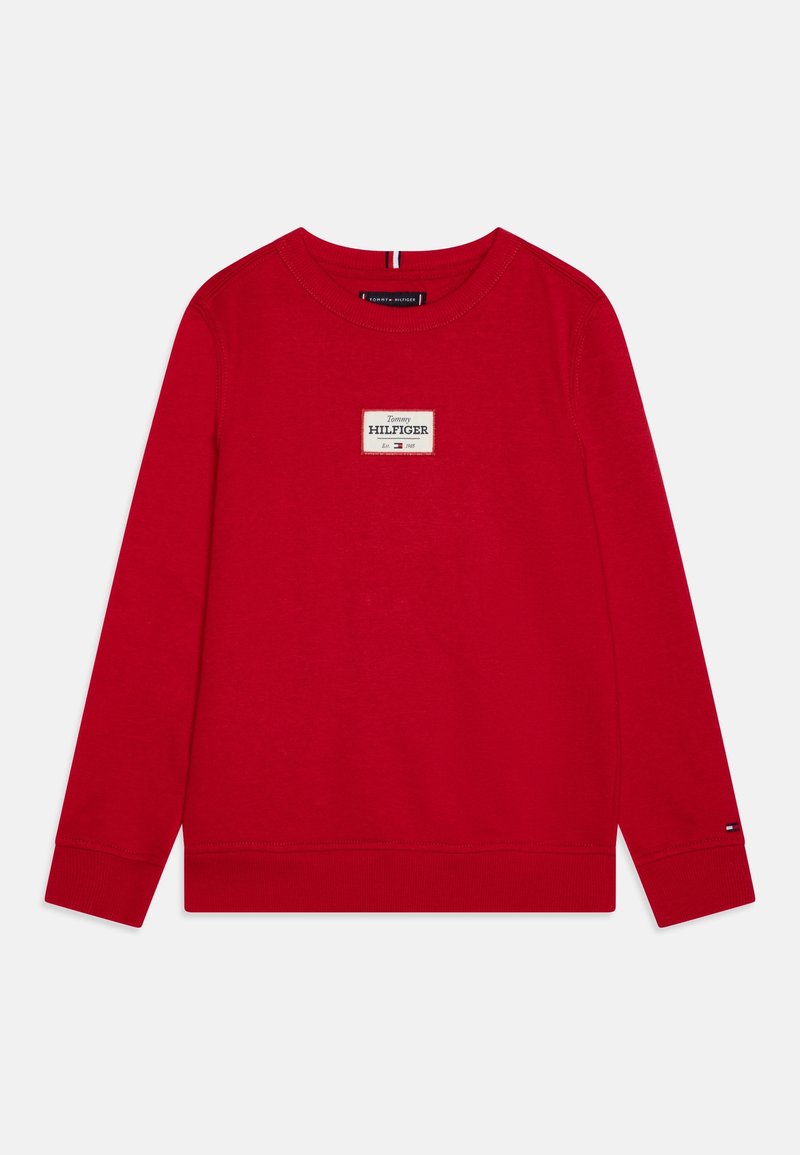 Sweat-shirt rouge à manches longues avec col rond, poignets et ourlet côtelés, présentant un patch rectangulaire du logo Tommy Hilfiger sur la poitrine.