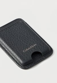 Μαύρος δερμάτινος κάτοχος καρτών με υφή και εγκοπή για εύκολη πρόσβαση. Διαθέτει ανάγλυφο λογότυπο Calvin Klein.