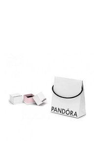 Borsa regalo bianca Pandora con manico nero, caratterizzata dal nome del marchio. Scatola rosa aperta accanto, anch'essa con logo del marchio su base bianca.