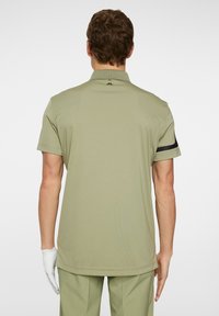 Kortärmad, olivgrön polo med svarta ränder på ärmarna, tillverkad av ett smidigt material, med en klassisk krage och en skräddarsydd passform.