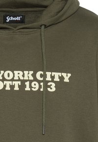 Sweatshirt à capuche vert olive en jersey de coton. Présente une impression de logo blanche portant la mention "NEW YORK CITY SCHOTT 1913" et des cordons assortis.