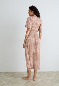 Vestido largo de suave tela rosa, con un estampado inspirado en la naturaleza, mangas cortas con volantes y una cintura elástica para un ajuste relajado.