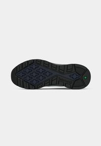 Melnā gumijas zole ar rakstainu profilu, kas satur sešstūra formas. Iekļauta Timberland zīmola apzīmējums un zaļa akcenta detaļa tuvu papēžam.