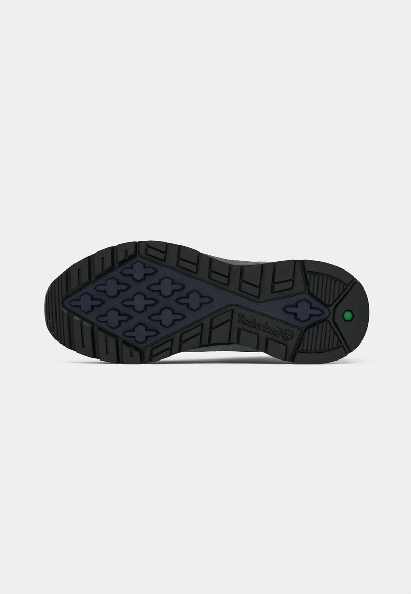 Black rubber sole with a patterned tread featuring hexagonal shapes. Includes Timberland branding and green accent near the heel.