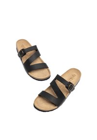 Black leather sandals with two crossed straps and a side buckle. Soft tan footbed with textured surface, rubber outsole for grip.