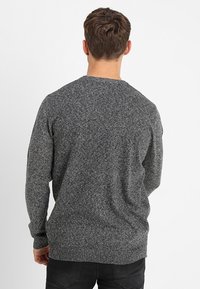 Suéter de punto gris con un acabado texturizado, cuello redondo y puños y bajo acanalados. Presenta un corte relajado.