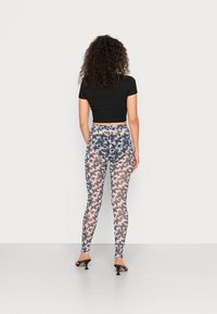 Top cropped preto emparelhado com leggings justas com um padrão de borboletas em tons de azul e castanho, sobre um fundo branco transparente.