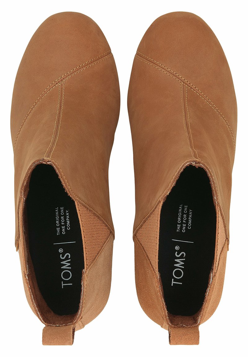 Botas de tobillo de cuero marrón con una textura suave, punta redonda y paneles laterales elásticos. El interior presenta una marca negra en la plantilla.