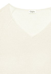 Nahaufnahme eines cremefarbenen Strickpullovers mit V-Ausschnitt und einem kleinen Etikett der Marke "Buffalo" am Kragen.