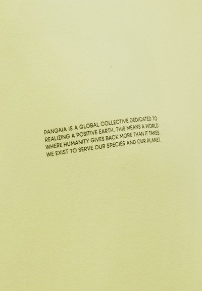 Κείμενο σε ανοιχτό κίτρινο ύφασμα αναφέρει την αποστολή της PANGAIA να δημιουργήσει έναν θετικό πλανήτη, επιστρέφοντας στην πανίδα και τον πλανήτη.