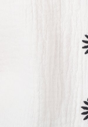 Tissu blanc avec un tissage texturé et des détails de broderie florale noire. Le design présente une apparence douce et tissée.