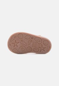 Καφέ σόλα παιδικού παπουτσιού με μοτίβα βάδισης εμπνευσμένα από τη θάλασσα, όπως κοχύλια, αστερίες και το όνομα της μάρκας "Pom D’Api" ανάγλυφα.