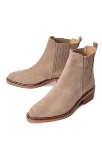 Beige mokasíny do členků z semiše s elastickými postranními panely, špičatou špičkou a zvýšeným podpatkem. Obsahuje kontrastní šev podél podrážky.
