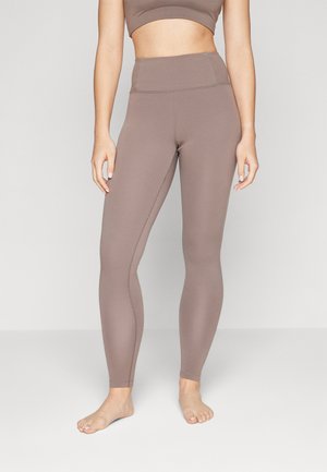 Brune leggings med høj talje, lavet af et glat, strækbart materiale. Simpelt design med diskret syning og ingen mønstre.