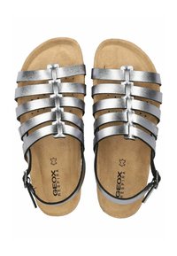 Sandali metallici argento con cinturini, dotati di una soletta in sughero, caratterizzati da una cinghia alla caviglia nera regolabile e un design open-toe.