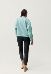 Miętowa bluza z długim rękawem i okrągłym dekoltem, w zestawie z czarnymi legginsami z panelami i wysokim stanem.