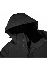 Giacca nera impermeabile con cappuccio, dotata di chiusura frontale con zip e bottoni a pressione, foderata in morbido tessuto e realizzata in un materiale liscio.