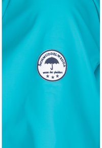 Turkusowa wodoodporna tkanina z okrągłą czarno-białą łatą z stylizowanym parasolem i tekstem. Gładka tekstura, prosty design.