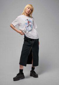 Gray t-shirt featuring a colorful graphic of a basketball player and the word "Ciao!" Skirt is black, long, with a zipper and side pockets.