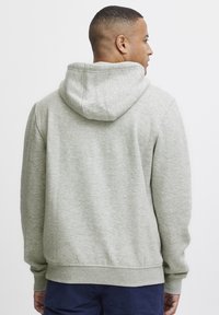 Light gray hoodie with a textured fabric, kangaroo pocket, and adjustable drawstring hood. Ribbed cuffs and hem.
