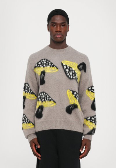 Grå sweater med livlige gule og sorte svampemønstre, lavet af et tekstureret, fuzzy materiale med en rund hals.