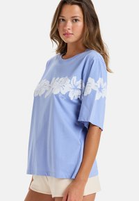 Lichtblauwe katoenen t-shirt met korte mouwen, voorzien van een witte bloemenprint aan de voorkant, relaxte pasvorm en ronde halslijn.