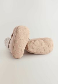 Ljusrosa tofflor med björngesiktsmönster på sulan, mjukt tyg på ovansidan och randig design. Rundad form med fluffig textur.