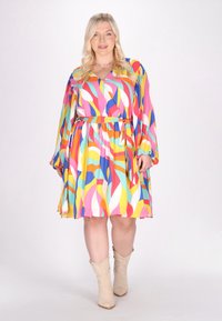 Rochie colorată, cu un model din forme abstracte, cu mâneci lungi, decolteu în V și talie cu fundă. Prezintă forme abstracte vibrante în nuanțe de roz, galben, albastru și verde. Purtați-o cu cizme bej.