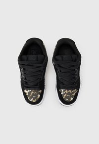Black sneakers with a textured fabric design, featuring a leopard print accent on the toe and white rubber soles. Laced and low-top style.