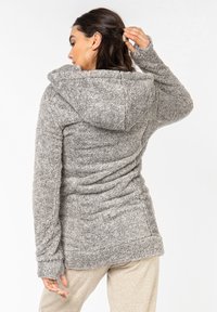 Gray, fuzzy hoodie with an adjustable hood, long sleeves featuring thumb holes, and textured fabric. Form-fitting design, soft finish.