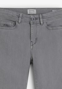 Jeans de mezclilla gris con un diseño clásico de cinco bolsillos, cierre de botón y una textura sutil. Presenta una etiqueta de la marca en la parte interior de la cinturilla.