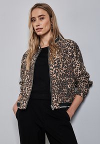 Veste bomber à imprimé léopard en tan et noir, dotée d'une fermeture à glissière, de poignets et d'un ourlet côtelés. Texture lisse avec une coupe décontractée.