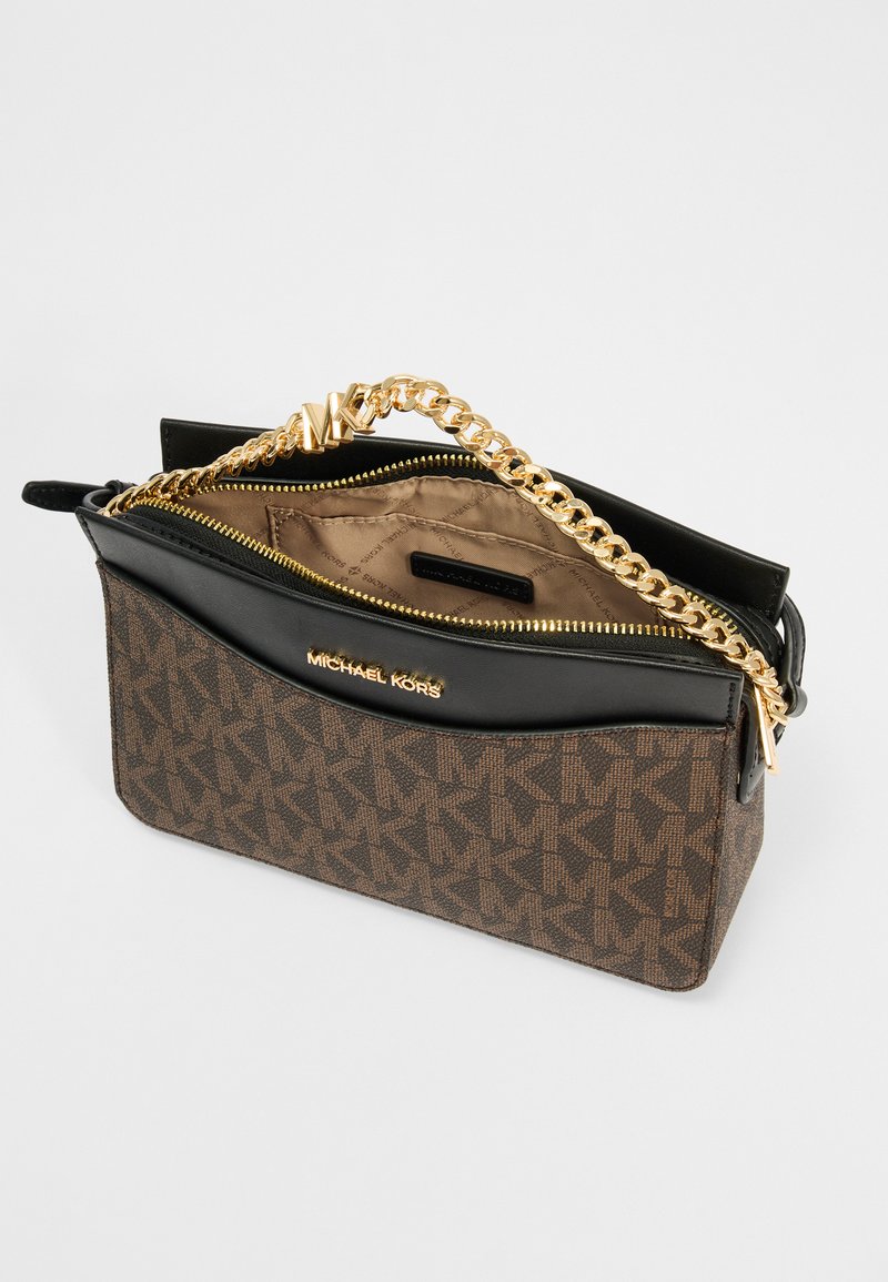 Bruine monogram canvas handtas met zwarte leren accenten, gouden kettingriem, ritssluiting en logodetails op de voorkant. Het interieur is beige.