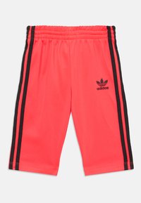 Adidas kratke hlače u svijetloj koraljnoj boji s crnim bočnim trakama. Imaju elastičnu pojasevnu traku i mali crni logo na lijevoj nozi.