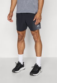 Zwarte sportshorts met stipaccenten, gecombineerd met een grijze gestreepte shirt, witte crew-sokken en zwarte sportschoenen met een witte zool.