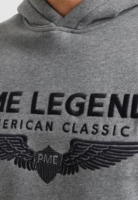 Felpa grigia con cappuccio caratterizzata da un logo ricamato con "PME LEGEND" e "AMERICAN CLASSIC", arricchita da design di ali e una finitura testurizzata.