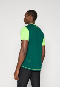 Πράσινο και φθορίζον κίτρινο αθλητικό μπλουζάκι με κοντά μανίκια, υφασμάτινη υφή, στρογγυλή λαιμόκοψη και αντίθετες λεπτομέρειες στο τελείωμα.