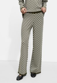 Ensemble de salon à carreaux verts et blancs comprenant un haut à manches longues et un pantalon large. Tissu doux avec finitions côtelées et une coupe confortable.