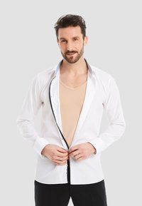 White dress shirt with black button accents, long sleeves, and a contrasting collar. Worn over a beige undershirt, with open front.