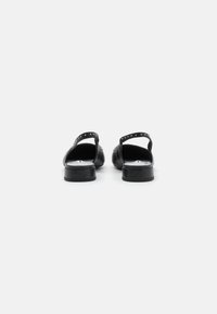 Melnas ādas slingback kurpes ar studu akcentiem, zemi blokveida papēži un atvērta aizmugure. Gluda tekstūra ar elegantu izskatu.