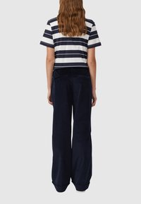 Gestreiftes T-Shirt in Marineblau und Weiß, mit kurzen Ärmeln und cropped Design, kombiniert mit lockeren, dunkelblauen Cordhosen.